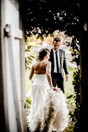 La mariée tenant la traine en plume de sa robe